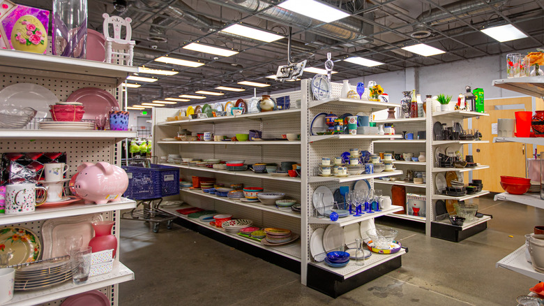 Thrift store shelves with dishware and items arranged by color