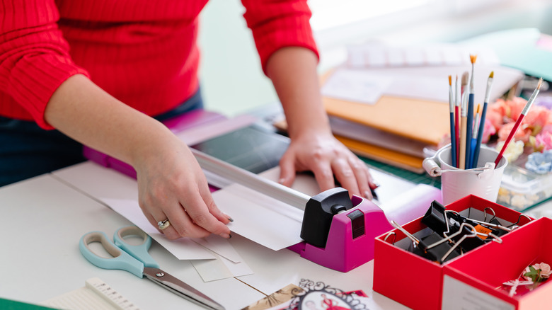 Woman cutting a white paper with a paper cutter