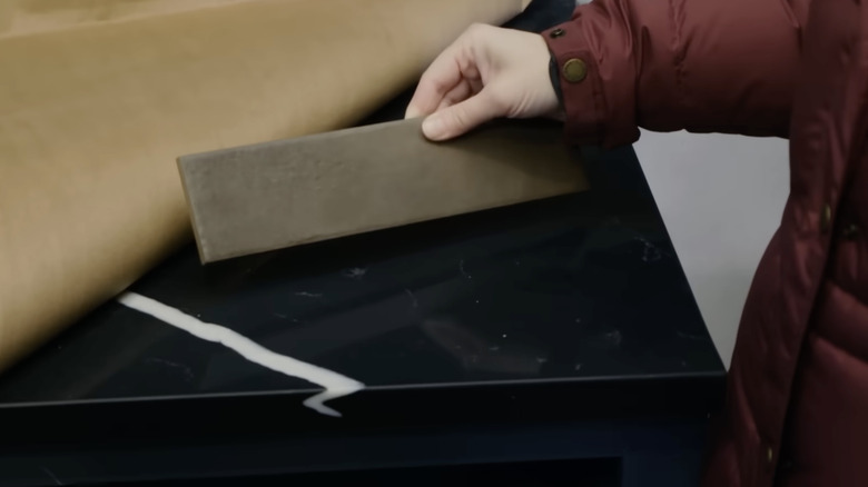 Erin Napier compares a brown backsplash tile with a black countertop