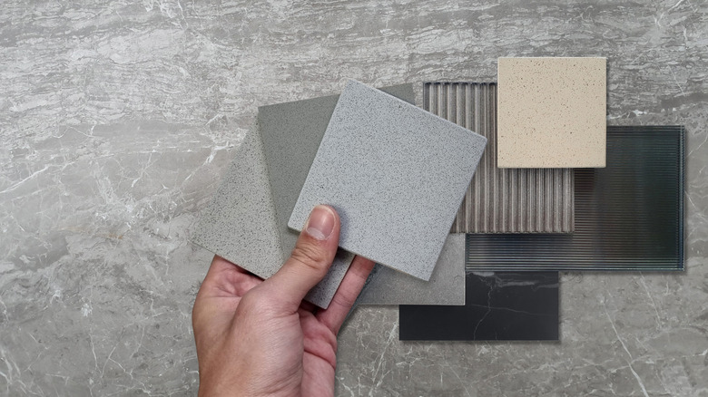 A hand holds different tile sizes and styles