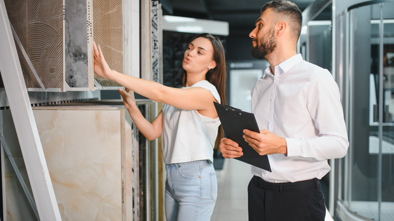 Salesman helping a woman choose tiles in a showroom
