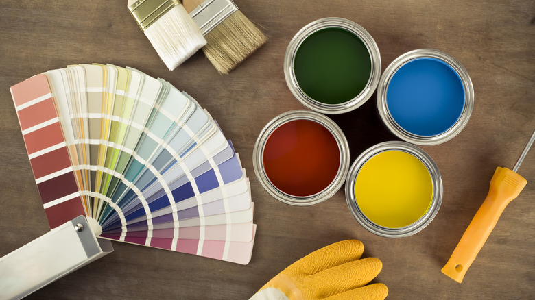 Various colors of paint cans and brush