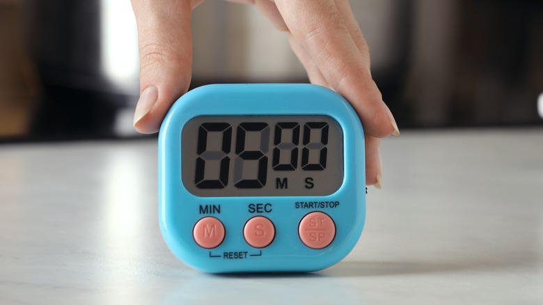 Hand pushing down a button on a timer in a kitchen