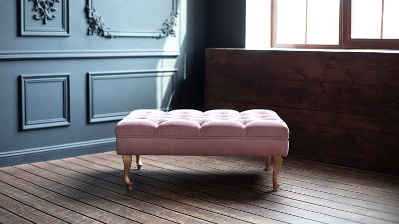 A pink ottoman on wooden floor in dark room