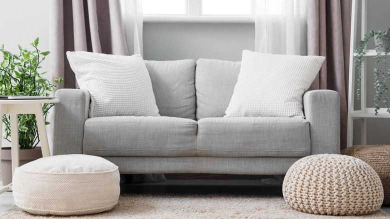 Living room with gray couch with two pouf pillows on floor