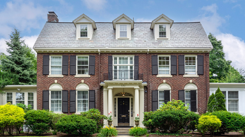 A classic colonial revival two-story brick family house with symmetrical design and window shutters.
