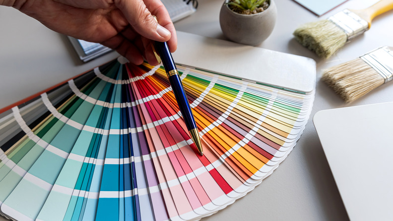 An interior designer pointing a paint swatches with a pen on their desk