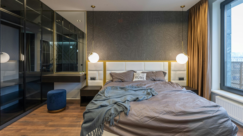 A navy blue pouf is positioned under a nightstand in a bedroom