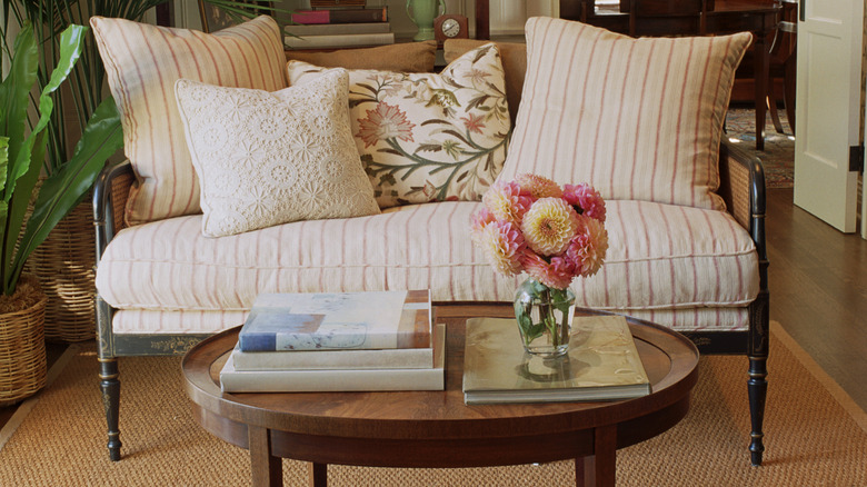 A small wooden table sits in front of a vintage settee