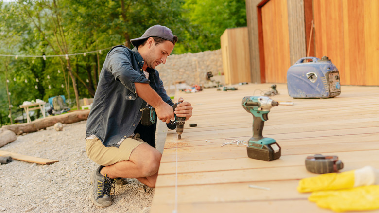 a DIYer building a wood deck, on his knees