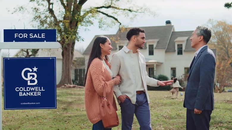 Young couple talking to Coldwell Banker real estate agent outside home