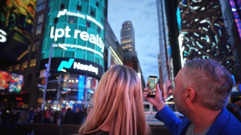 LPT Realty founder Robert Palmer taking picture of company sign on building company name