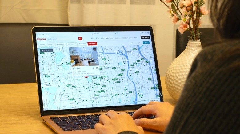 Person browsing Redfin listings on laptop