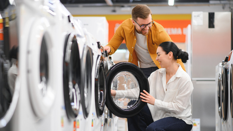A couple checks out washing machines at an appliance center.