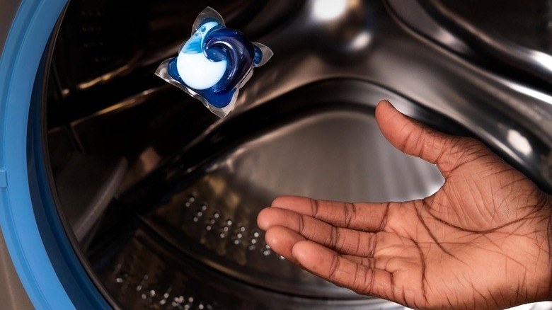 Person tossing a Tide pod into the washing machine