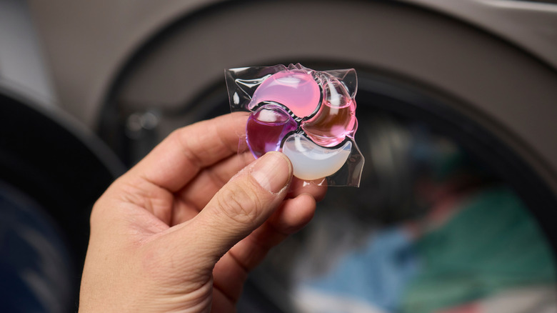 Person adding a laundry detergent pod to the washing machine