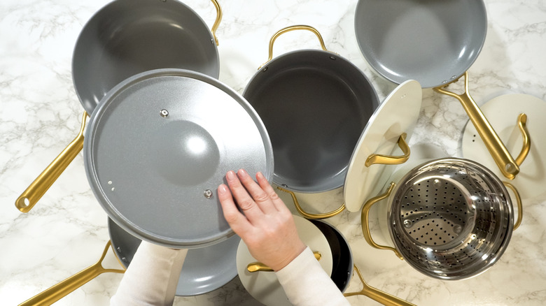 Scattered pots and pans with person holding pot lid