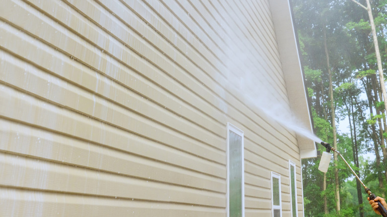 man pressure washing vinyl siding