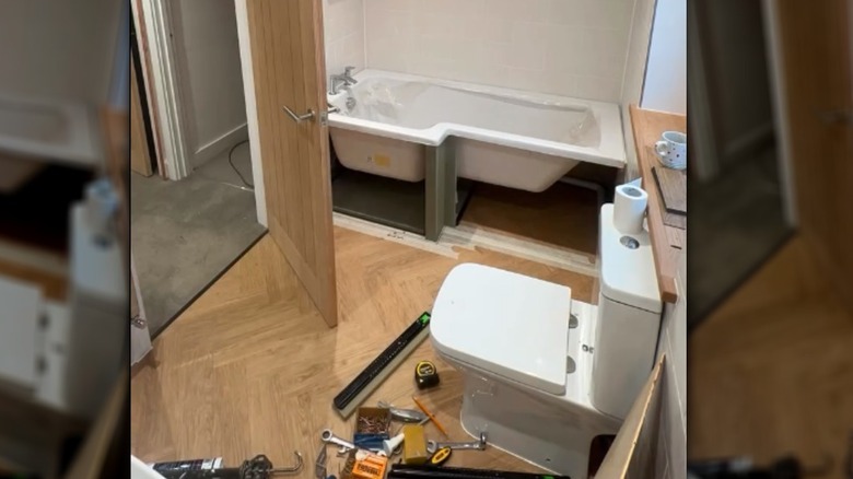A mirrored image of a bathtub cabinet install in progress