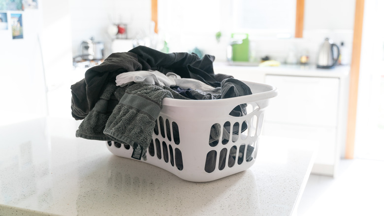 Clothes sitting in a hamper on top of the counter.