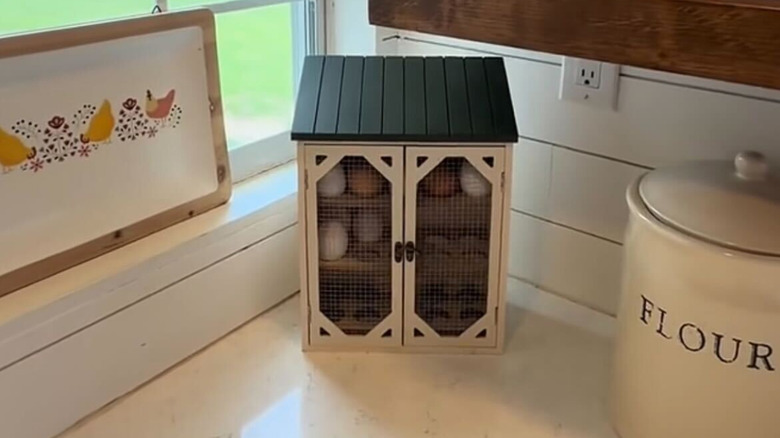 Countertop chicken coop egg holder sitting next to a chicken print and a flour crock
