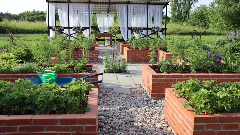 vegetables and flowers in a raised brick beds laid out in a symmetric design with gravel and paved walkways