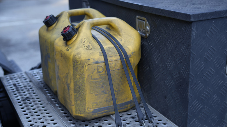 Diesel fuel cans strapped into bed of truck.