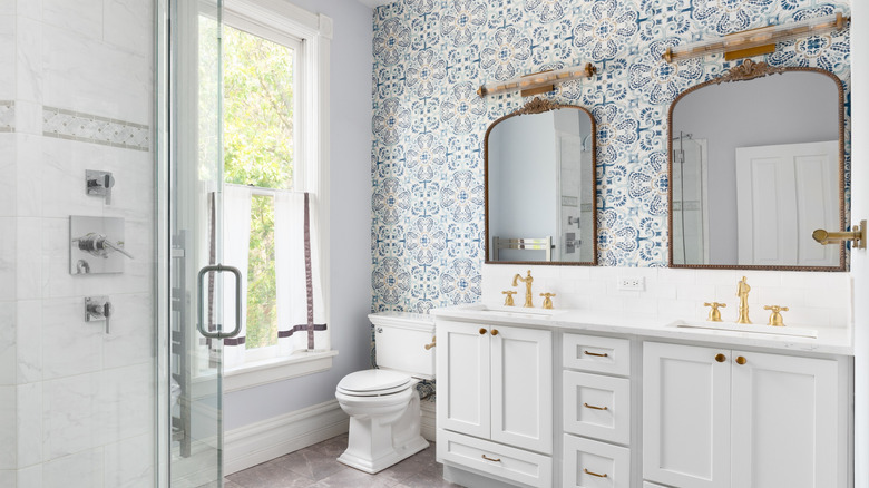 Bathroom wall with double sink vanity has wallpaper on the walls