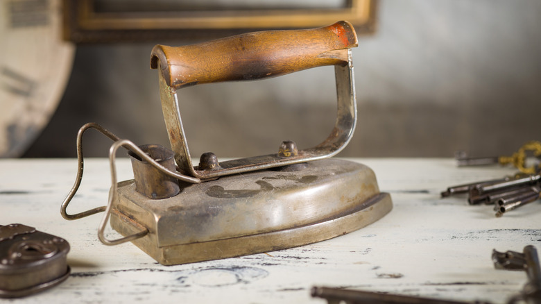 An antique iron sits on a table next to an antique lock and keys.