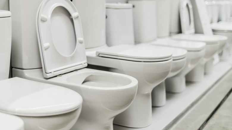 A row of closed and open white toilets.
