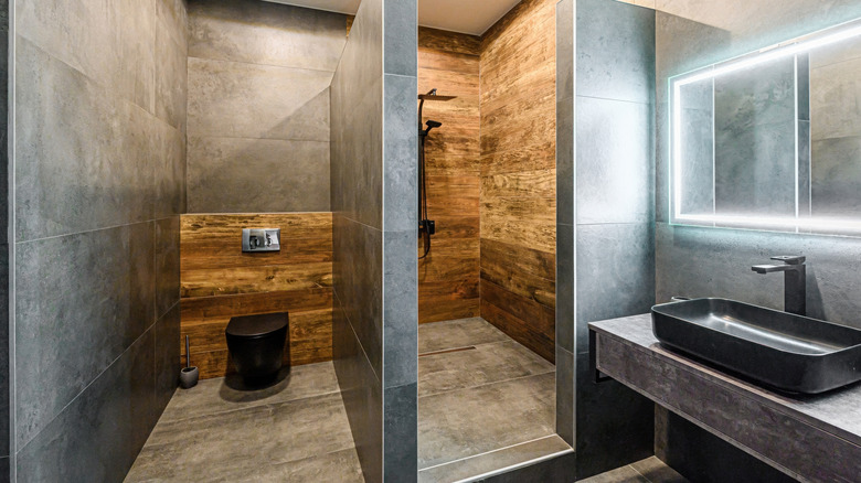 A modern bathroom with black fixtures, tile, and wood.
