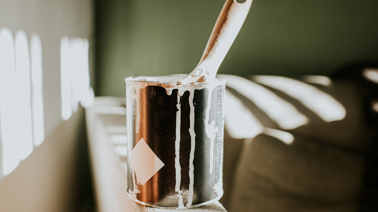 A can of paint by freshly painted walls in sunny room