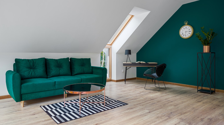 A small living room with emerald green wall and couch
