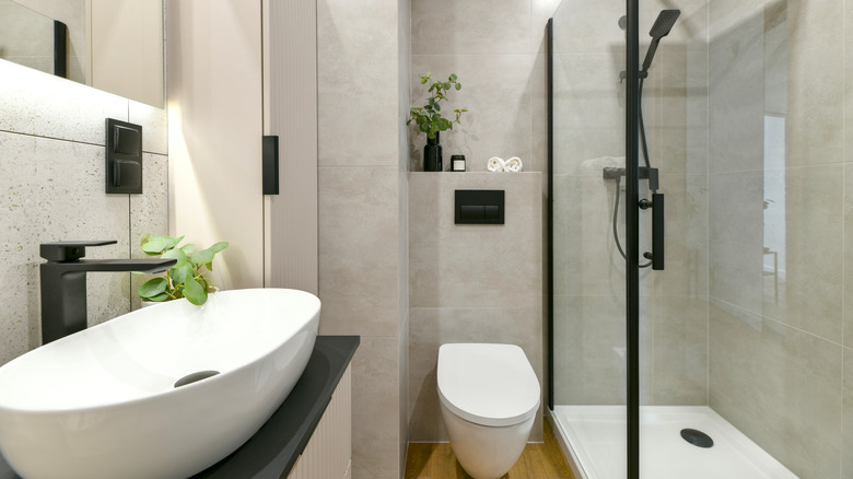 A monochromatic bathroom with two green plants