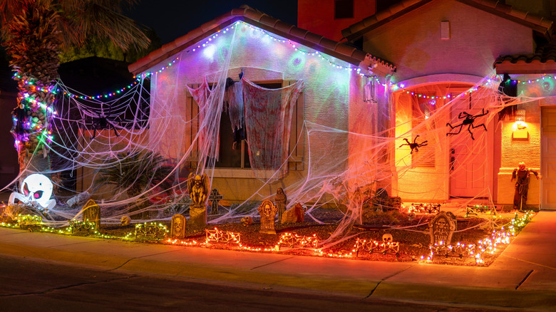 Home decorated for Halloween with large woven cobwebs, fake spiders, graveyard stones, and orange lighting effects