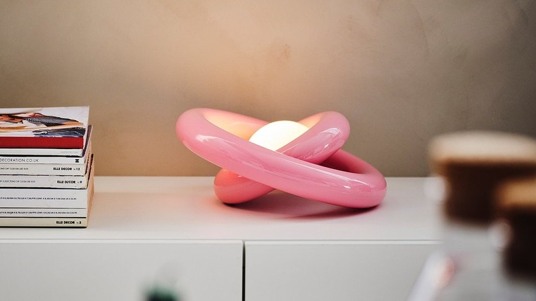 Pink STRÅLA lamp with rings askew on cabinet