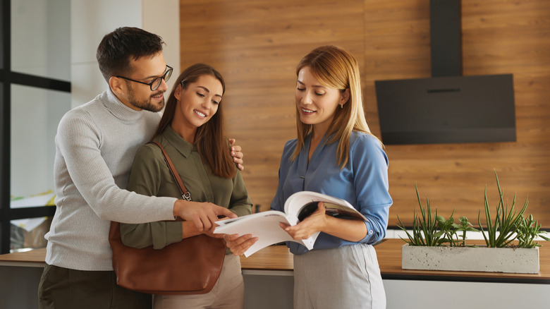 A couple shops for kitchen designs with the help of a female employee