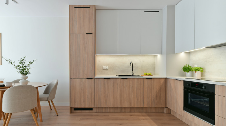 White oak cabinets in a clean, minimalist kitchen, dining room table to the left of the kitchen.