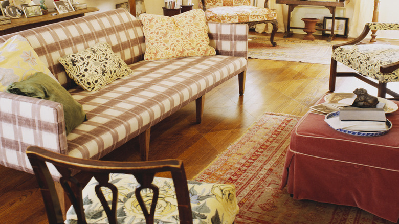 Cozy living room depicting a gingham pattern chair, botanical pattern pillows, vintage furniture, and soft elements.
