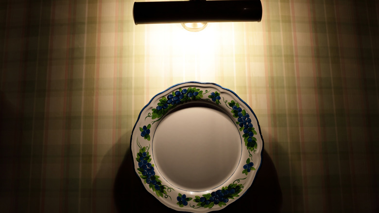 Light above decorative plate on wall