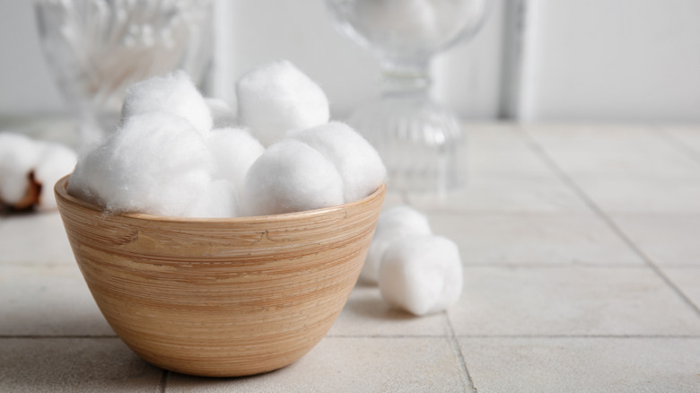Cotton balls in a wooden bowl sitting on a bathroom counter