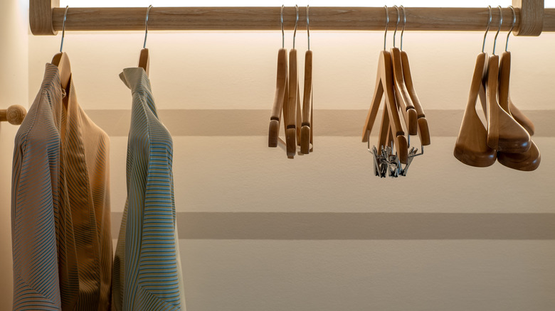 An empty closet with two bathrobes hanging from the closet rail and some nice wooden hangers.