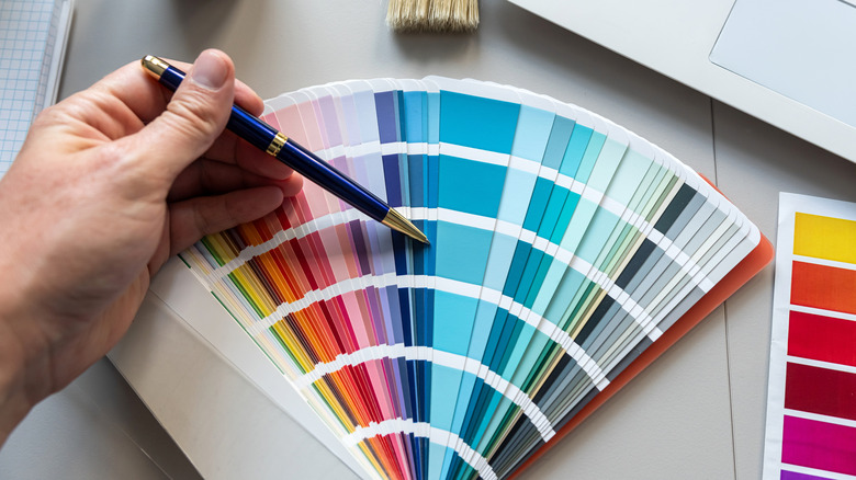 A hand with a pen pointing at a color swatch.