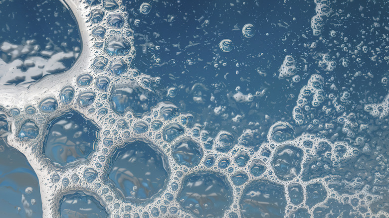 Soap bubbles floating on blue water.