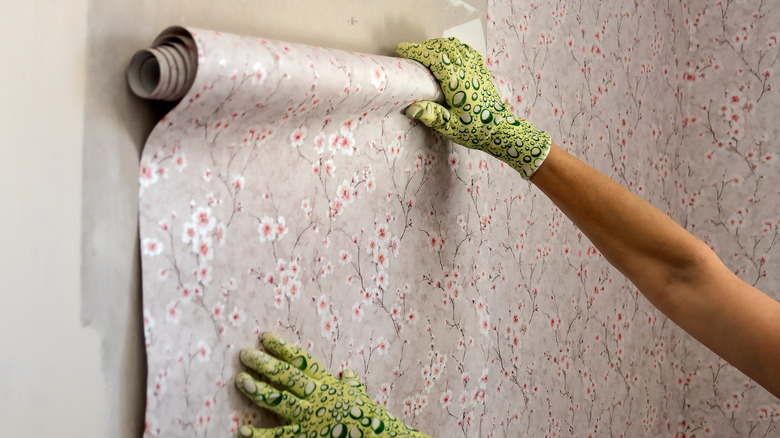 Person applying floral wallpaper