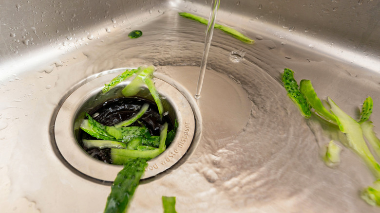 food being put in a sink garbage disposal