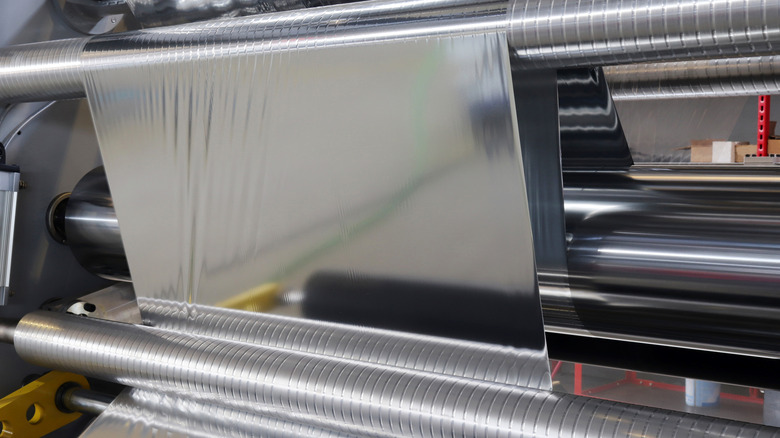 Large sheet of aluminum foil being rolled out during the manufacturing process