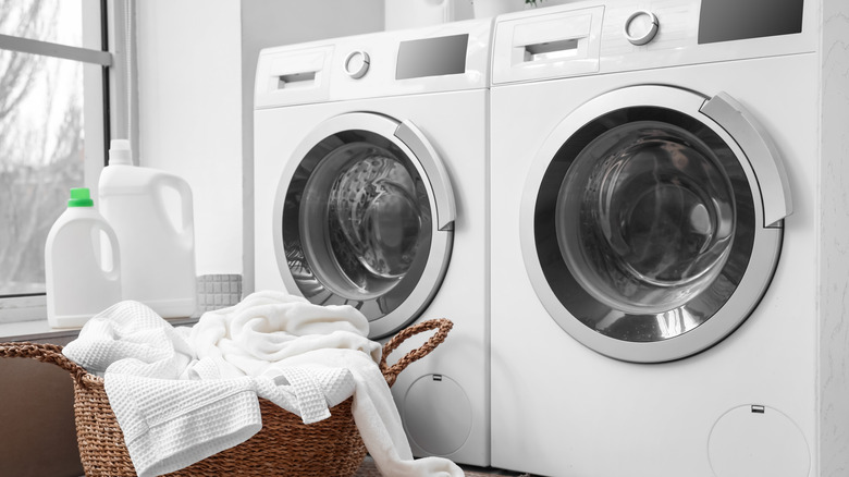 White washer and dryer with laundry basket in front.
