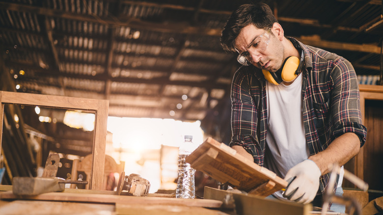 A man looks at a woodworking project in his workshop