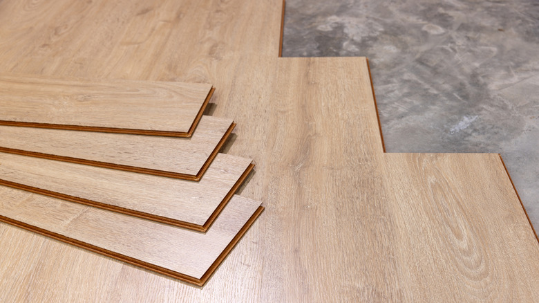 Luxury vinyl plank flooring made to look like wood being installed over stone floors